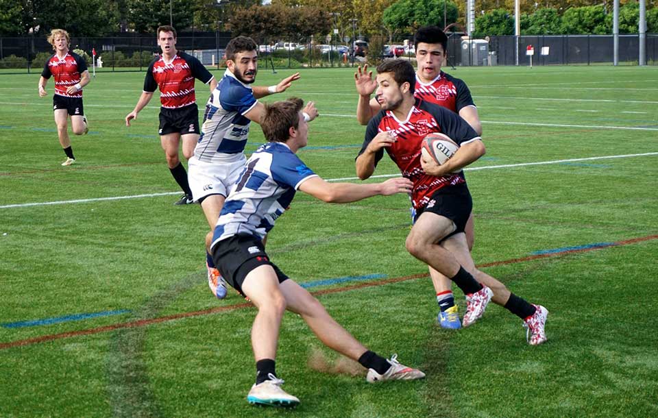 Men playing rugby on a grassy field.