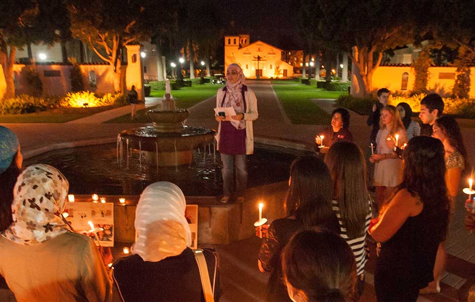 People gathered at night holding candles for a vigil.