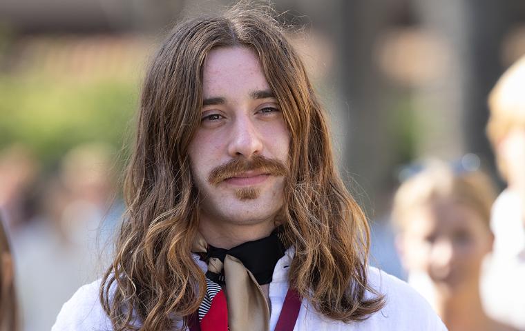 Simon Lanzoni wearing a white shirt, looking into the distance at the Senior Toast image link to story