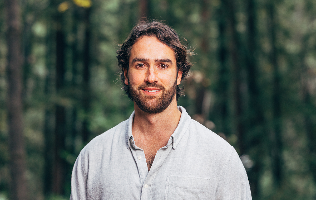 Sean Reilly standing in the woods wearing button up white shirt