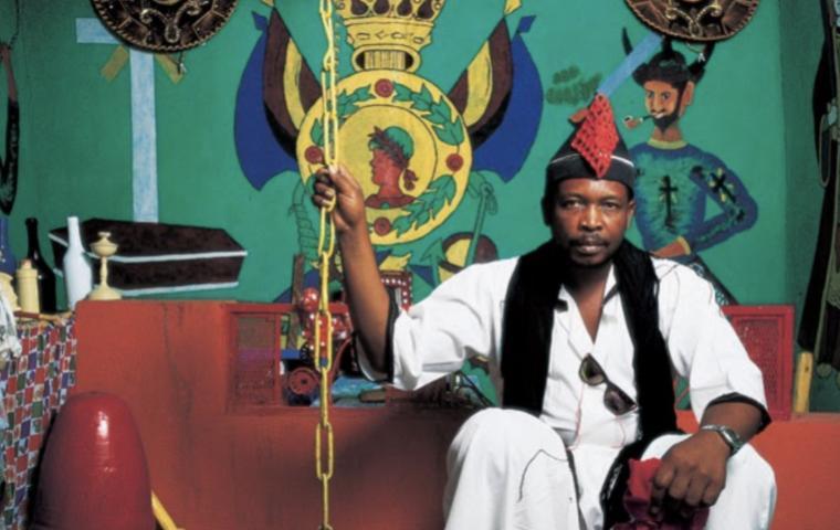 Photograph of vodou priest Volny Derosier, seated in his vodou temple in La Petite Rivière de l'Artibonite, Haiti. Photo courtesy of Haiti ©Phyllis Galembo.