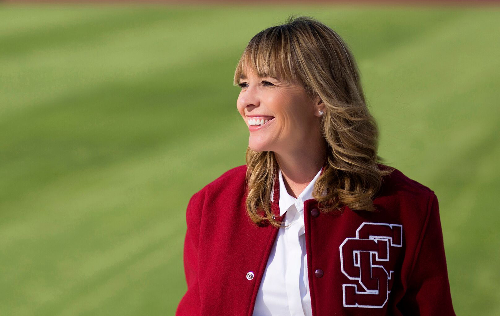 Person in a red jacket smiling on a field.