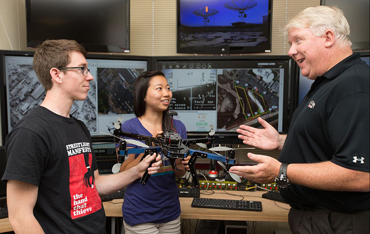 Chris Kitts working with two students in the Robotics Lab.