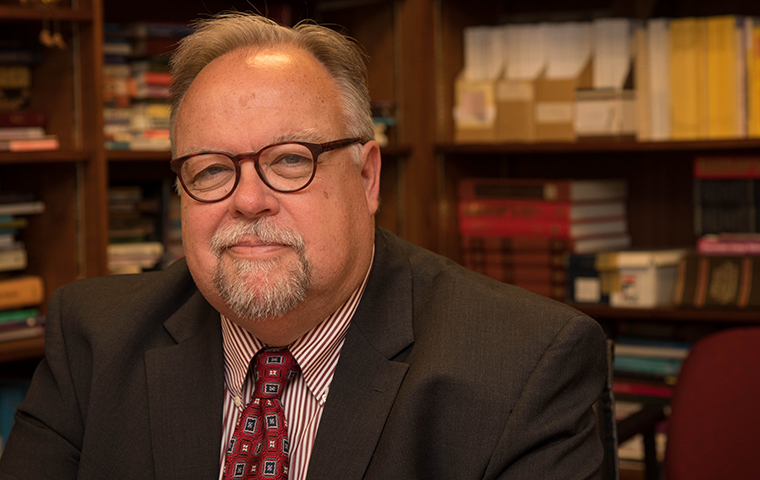 Don Heider sits in front of a book shelf