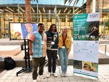 Three students stand together near a science fair exhibit.