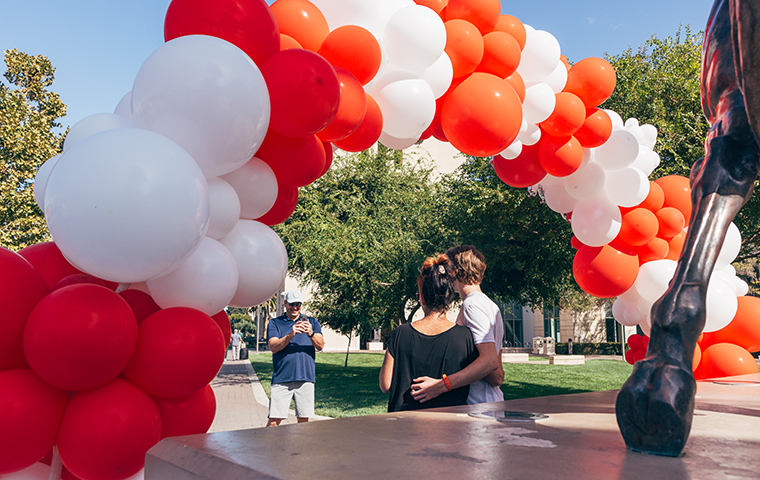 A family taking a photo under balloon arch at Santa Clara U.