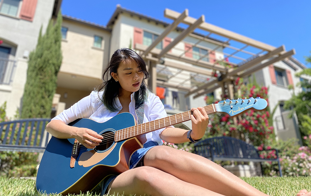 Primrose Waranimman plays guitar in grass