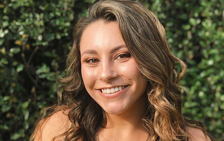 Alex Hagerty stands in front of a plant