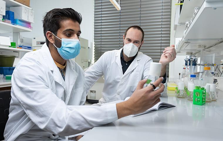 Brian Bayless sits with student who examines glass bottle
