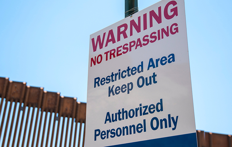 US Homeland Security sign at Mexican Border with fence in the background