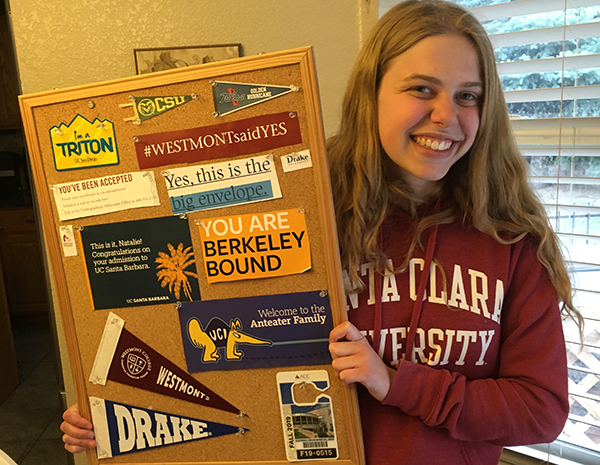 Natalie Plaia holding a cork board full of bumper stickers