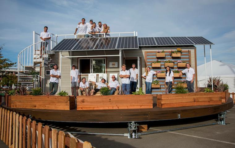 A team posing in front of a modern, solar-paneled building.
