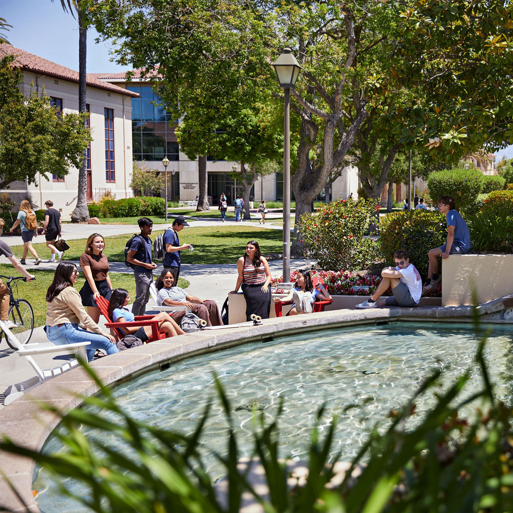 Students gather around the fountain during a sunny day on campus