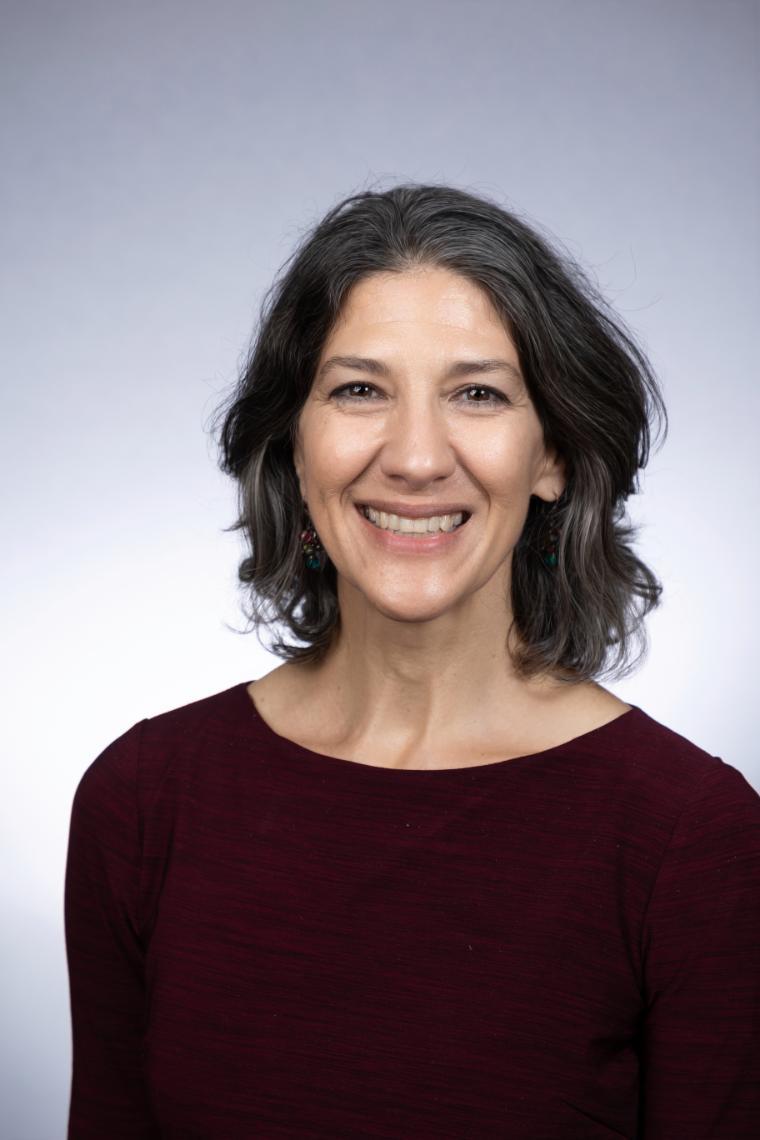 A person smiling against a grey background.