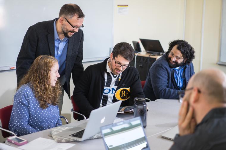 People working together with laptops and documents in a meeting room.