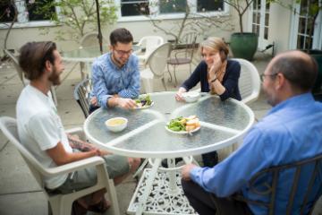 Four people sitting around a table having a discussion outdoors.