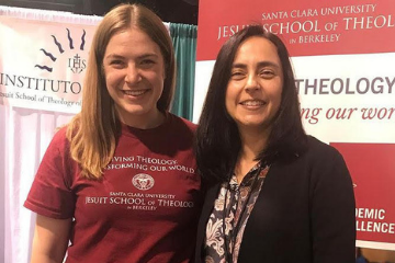 Two women standing in front of a red banner 