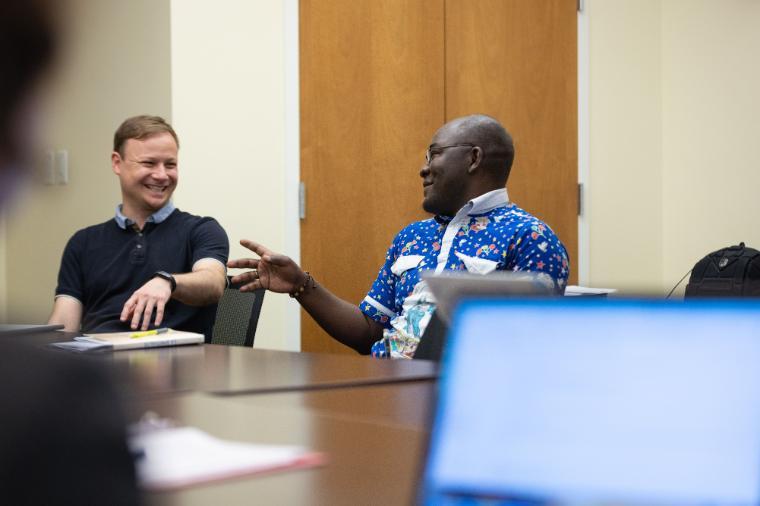 Two people laughing and talking in a classroom setting.