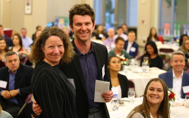 People standing and sitting around tables at an event.