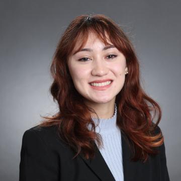 A person smiling, wearing a black jacket and light shirt.