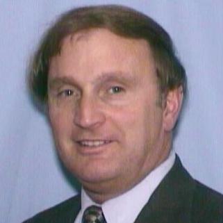 A man in business attire against a blue background.
