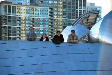 Three people walking in front of modern buildings in Chicago.