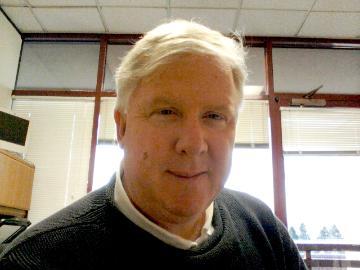 A person in an office with large windows behind them.