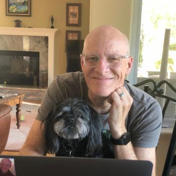 A person smiling while working on a laptop at home.