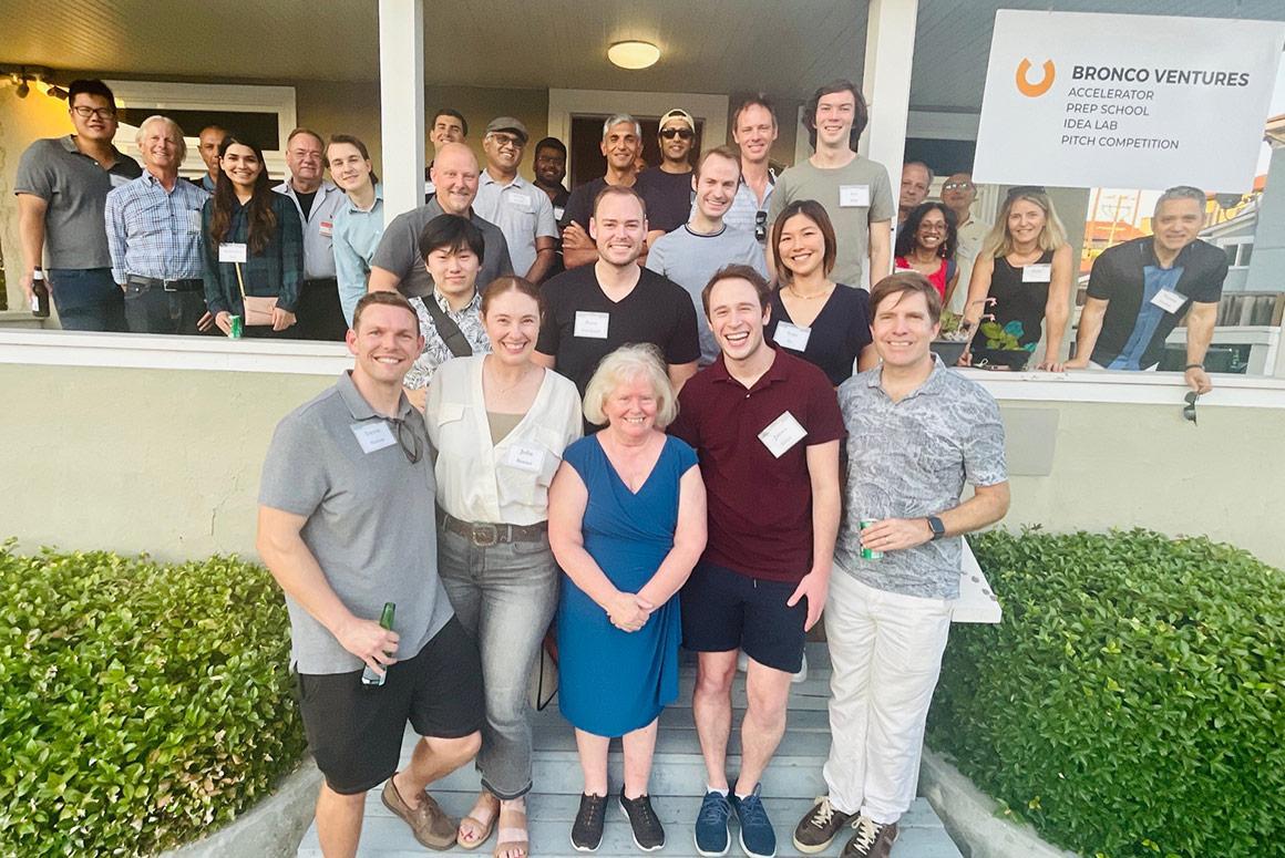 Group of people outdoors, under a porch, with a sign reading Ciocca Center Mentors.
