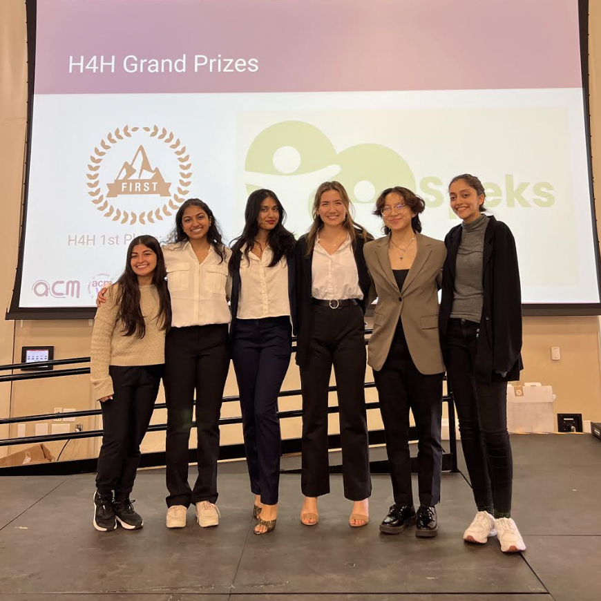 Six people standing together onstage with logos in the background, H4H Winners '23.
