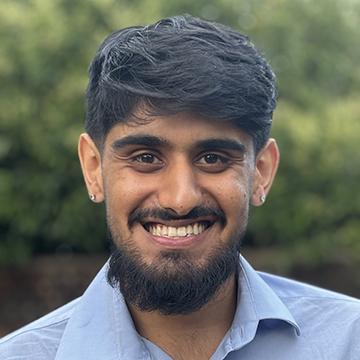 Bearded man smiling in blue shirt outdoors