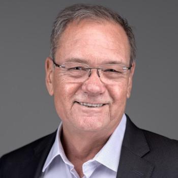 A person smiling in a suit with glasses.