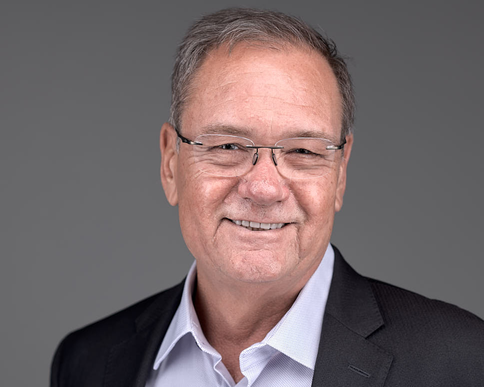 A person smiling in a suit with glasses.