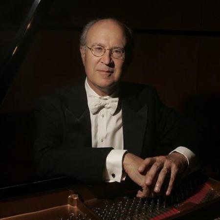 A man in formal attire seated at a grand piano.
