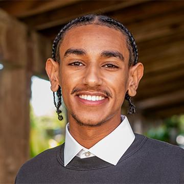 Man in gray sweater and white shirt smiling
