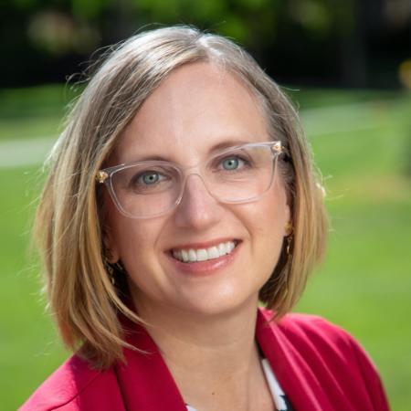 A person in a red blazer smiling outdoors.