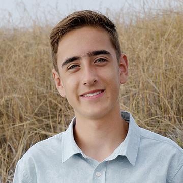 Man in blue shirt outdoors smiling