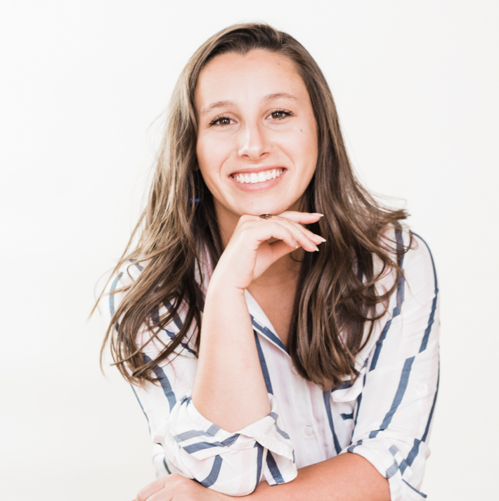 A person smiling with a hand resting on their chin.