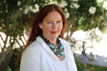 A woman in a white blouse and scarf outdoors.