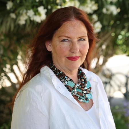 A woman in a white blouse and scarf outdoors.