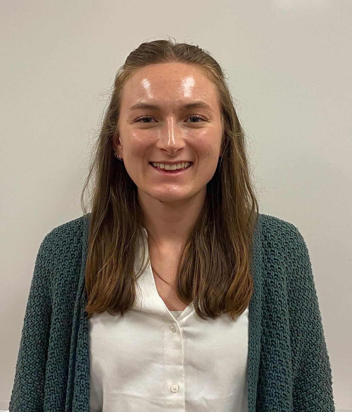 Woman in green sweater and white top smiling