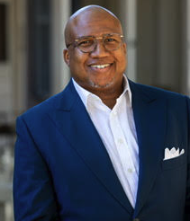 A person smiling in a blue blazer with a white shirt.