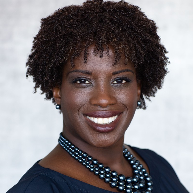 A person in a blue outfit smiling against a light background.