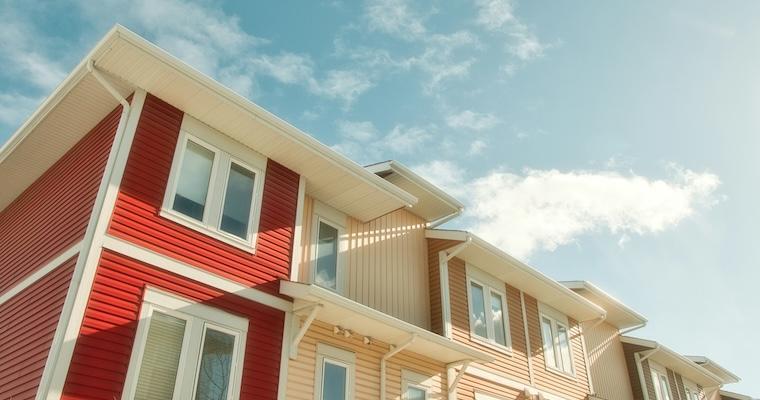 A row of multi family houses with a blue sky in the background 