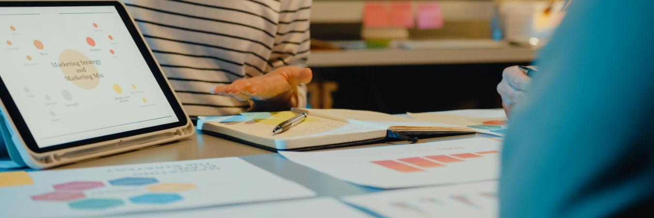 Team of professionals reviewing graphs and data on a tablet during a marketing meeting in modern office