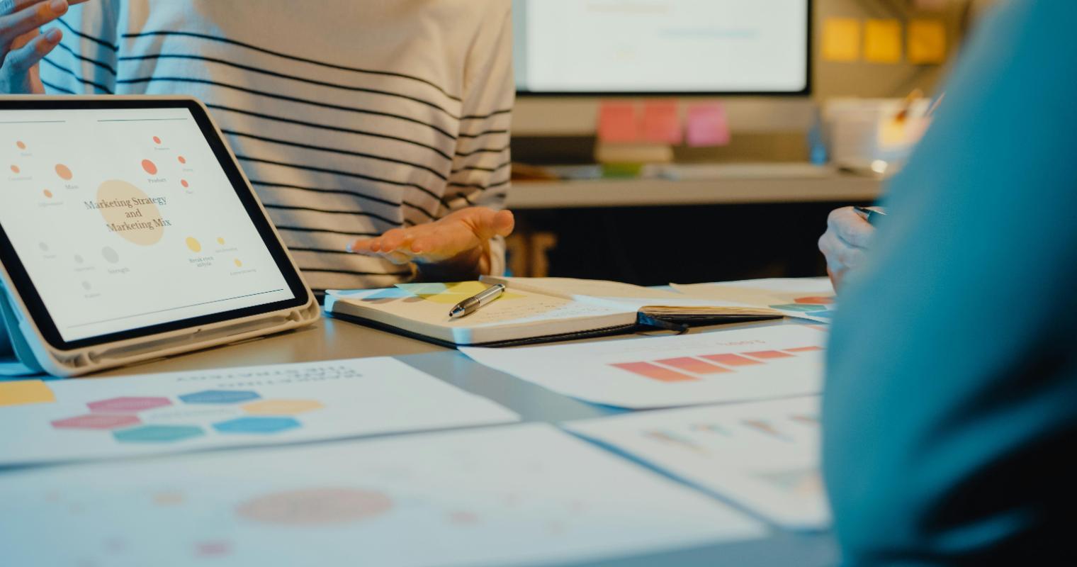Team of professionals reviewing graphs and data on a tablet during a marketing meeting in modern office