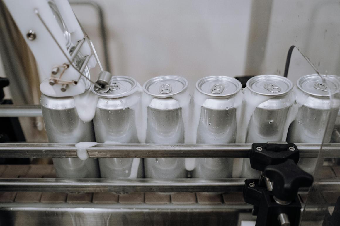 Unlabeled beer cans being filled on an assembly line