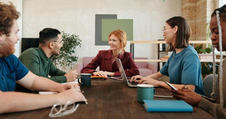 Five professionals engaged in a meeting around a conference table image link to article