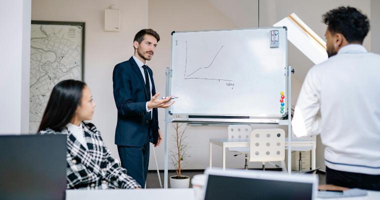 Business professional in suite explaining graph to colleagues image link to article