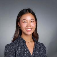 Portrait photo of Katie Eng smiling against a grey background.